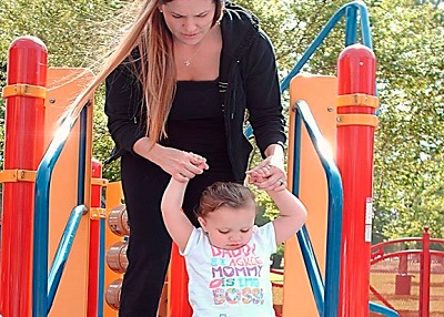 a Mom plays with her child on a slide at the sensory playground